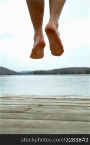 Feet jumping of cottage dock into water.