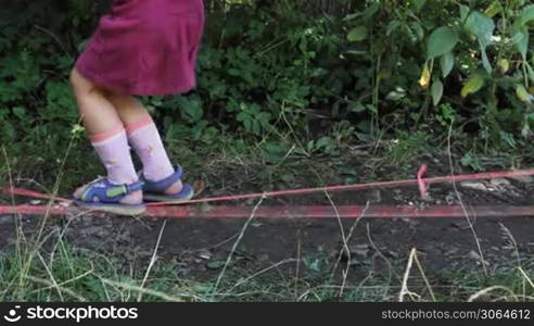 feet little girl come into frame and jump through two stretched rubber bands, then go away