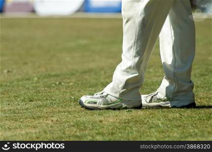 feet of a cricketer in traditional white trousers