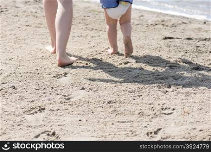 Feet of a woman and baby at a beach. Feet of a woman and a baby at a beach with footprints