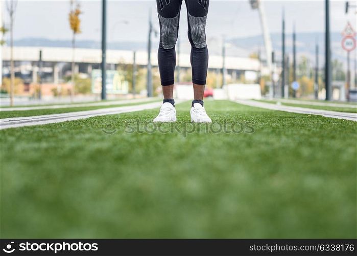 Feet of black man ready to running in urban background. Male doing workout outdoors.