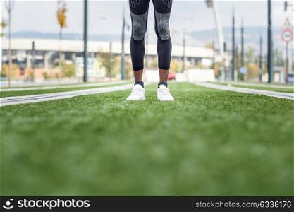 Feet of black man ready to running in urban background. Male doing workout outdoors.
