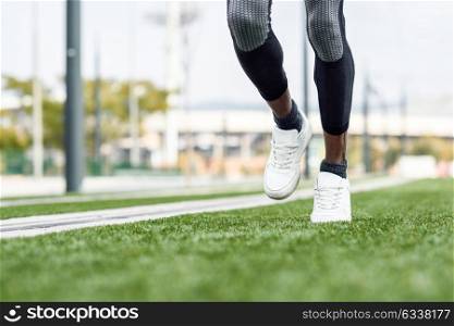 Feet of black man starting running in urban background. Male doing workout outdoors.