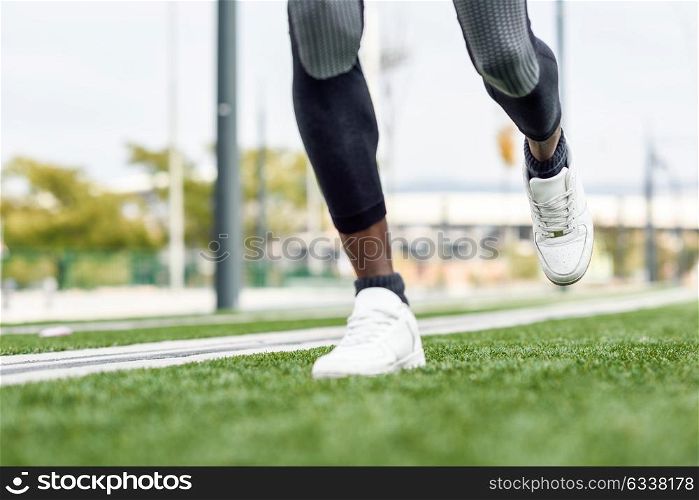Feet of black man starting running in urban background. Male doing workout outdoors.