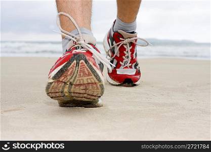 Feet of man jogging on a beach