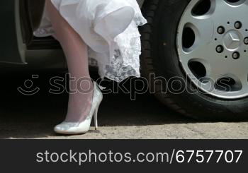 feet of the bride in a wedding dress coming out of the car