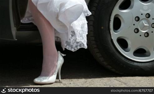 feet of the bride in a wedding dress coming out of the car