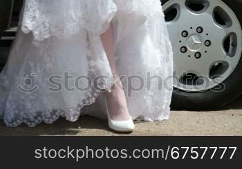 feet of the bride in a wedding dress coming out of the car