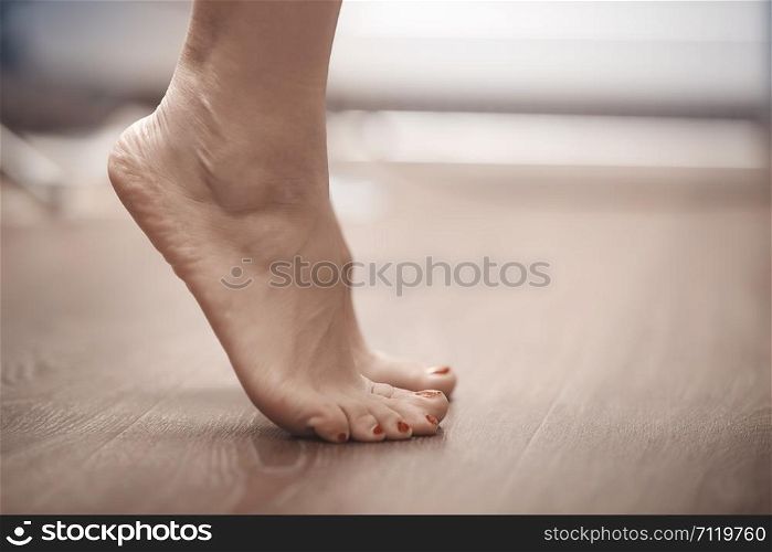 Feet of woman standing on tiptoe at home