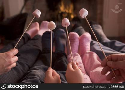 Feet warming at a fireplace with marshmallows on sticks