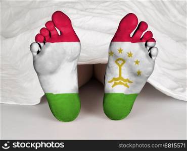 Feet with flag, sleeping or death concept, flag of Tajikistan