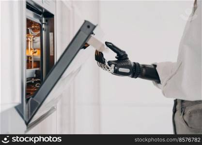 Female amputee is cooking using futuristic high technology bionic prosthesis. Robotic cyber hand of disabled person, which is standing in front of oven at kitchen. Daily routine of disabled.. Female amputee is cooking using futuristic high technology bionic prosthesis. Daily routine.