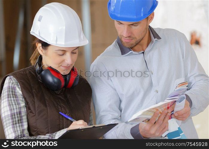 female and male construction worker discussing over clipboard