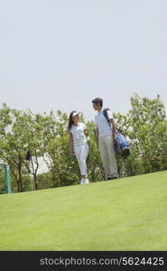 Female and male golfers talking and walking on the golf course