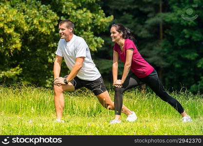 Female and male runner stretching in nature