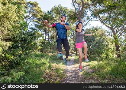 Female and male runners jumping mid air in park, Split, Dalmatia, Croatia