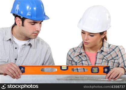 female apprentice and carpenter using ruler