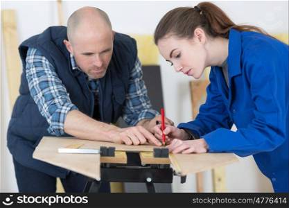 female apprentice and carpenter using ruler