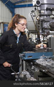 Female Apprentice Engineer Working On Drill In Factory