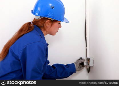 Female apprentice installing a power socket