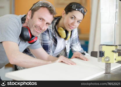 female apprentice learning to use bench saw