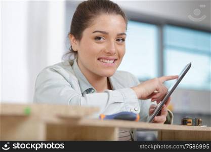 female apprentice using a tablet in furniture workshop