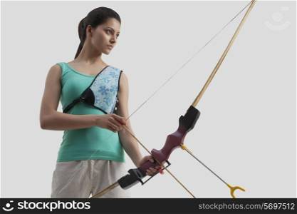 Female archer with bow and arrow isolated over gray background