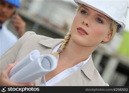 Female architect in a hardhat carrying plans