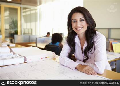Female Architect Studying Plans In Office