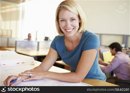 Female Architect Studying Plans In Office