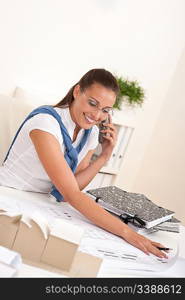 Female architect with phone sitting at office, architectural model on desk