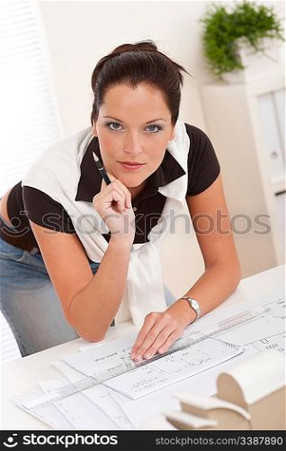 Female architect working at the office with plans and architectural model