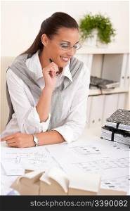 Female architect working with plans at the office holding pen