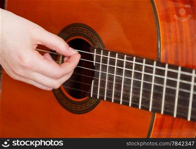 female arm plays on acoustic guitar close up