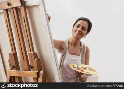 Female artist painting on canvas isolated over gray background