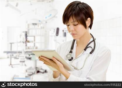 Female Asian American doctor using tablet computer in surgery