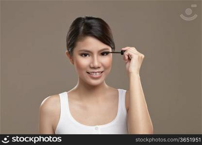 Female asian applying mascara