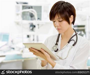 Female Asian doctor using tablet computer in clinic lab