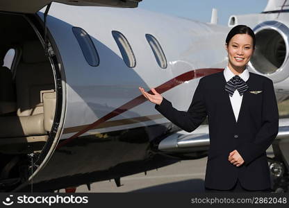 Female Asian mid-adult flight attendant in front of private jet.