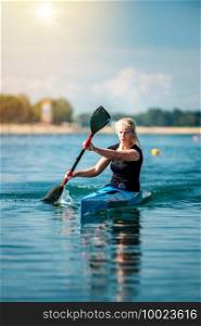 Female athelete training kayaking on lake