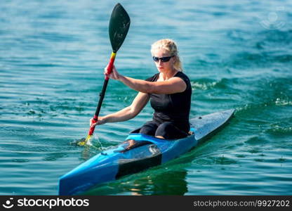 Female athelete training kayaking on lake