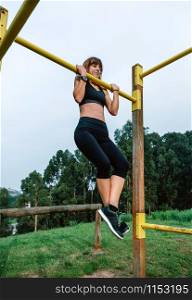 Female athlete doing pull up exercises in a park. Female athlete doing pull up exercises