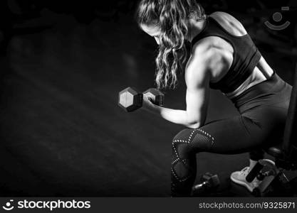 Female Athlete Exercising with Dumbbells in the Gym.