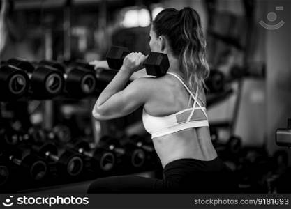 Female athlete exercising with dumbbells in the gym, black and white. Female Athlete Exercising with Dumbbells in the Gym.