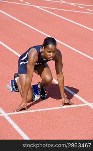 Female athlete in starting block, ready to run