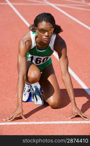 Female athlete in starting block, ready to run