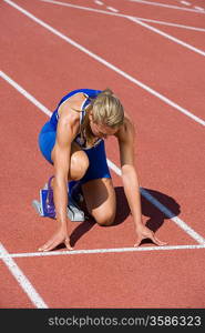 Female athlete in starting block, ready to run