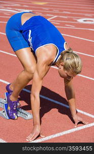 Female athlete in starting block, ready to run