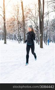 Female athlete jogging on park on winter day in park