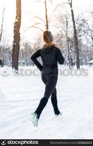 Female athlete jogging on park on winter day in park